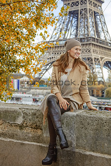 woman looking into distance while sitting on parapet in Paris