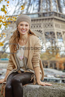 tourist woman sitting on parapet on embankment near Eiffel tower