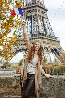 smiling tourist woman on embankment in Paris, France rising flag