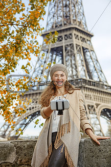 elegant woman taking selfie using selfie stick in Paris, France