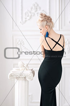 Portrait of a beautiful young sexy blond woman with  gentle makeup in  slinky black dress well maintained body and face