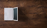 White laptop on a dark wooden desktop