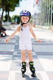 Little girl rides on roller skates at park