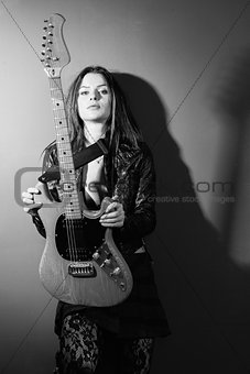 Serious woman standing with electric guitar