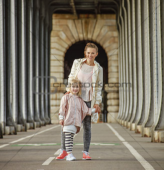 active mother and daughter standing on Pont de Bir-Hakeim bridge