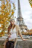 woman with map looking into distance on embankment in Paris