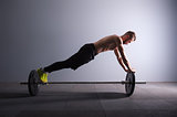 one man exercising fitness plank position on the barbel exercises in studio silhouette dark key
