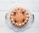 Chocolate cream cake on white wood with cake lace