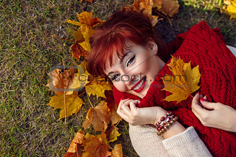 Red hair girl lying with autumn maple leaf