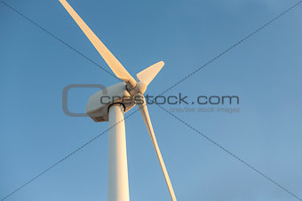 Electric wind turbines farm with sunset light on arid landscape