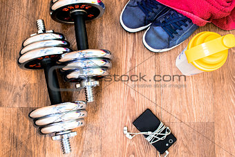 sports equipment on the wooden floor with sneakers, telephone, h