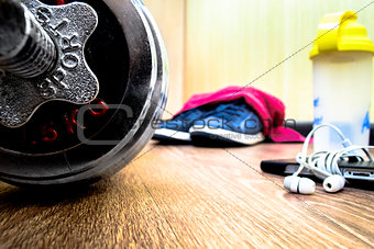 sports equipment on the wooden floor with sneakers, telephone, h