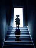 Little girl on steps leading from a dark basement to open the do