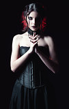 Dramatic portrait of beautiful goth woman among the dark