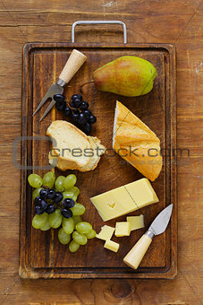 cheese board with grapes, pear and baguette