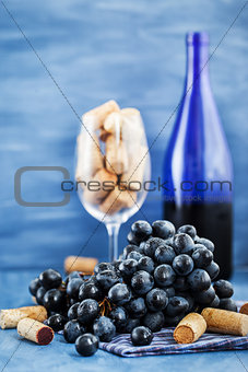 Branch of purple grape and wine corks on gray