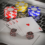 laptop with chips, dices and poker cards