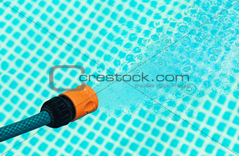 High pressure water from a hose flowing into a pool - closeup