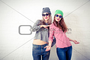 Two Happy Smiling Hipster Girls at White Wall