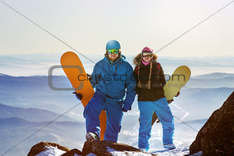 Two snowboarders stands on the top of mountain