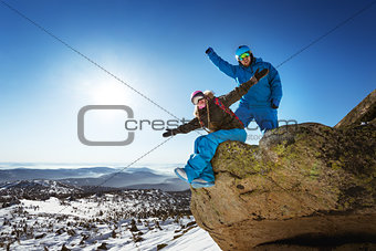 Happy snowboarding couple on the top of winter mountains
