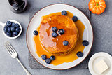 Pumpkin pancakes with maple syrup and blueberries on a plate Grey stone background Top view