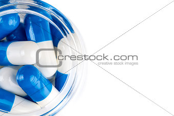 Blue white capsules in clear glass container top view