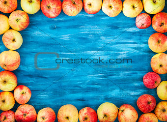 Frame of fresh red apples on painted blue wooden background