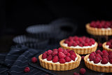 Delicious raspberry mini tarts on dark background