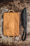 Chopping board and old knife on rustic table