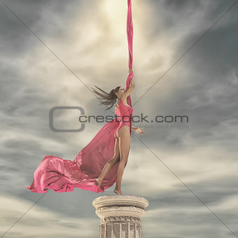Young beautiful girl sits on a column 