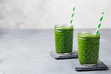 Spinach smoothie Healthy drink in glass jar on grey stone background. Copy space
