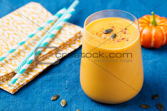Pumpkin smoothie with pumpkin pie spices on a blue wooden background