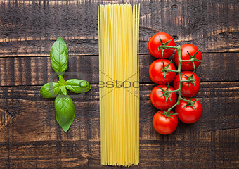 Fresh tomatoes with raw spagetti and basil on gunge background
