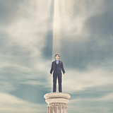 Businessman standing on a column 