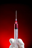 Syringe vertical pushing blood isolated on red 