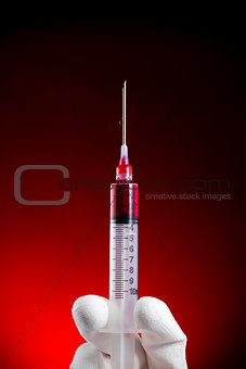 Syringe vertical pushing blood isolated on red 