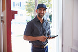 Courier Standing At Front Door With Digital Tablet
