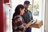 Woman Signing For Package From Courier At Home