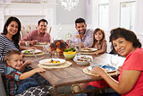 Extended Hispanic Family Enjoying Meal At Table