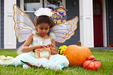 Girl Dressed In Trick Or Treating Fairy Costume On Lawn