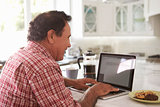 Senior Hispanic Man Sitting At Home Using Laptop