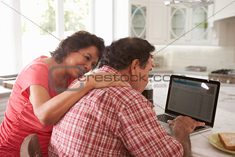 Confused Senior Hispanic Couple Sitting At Home Using Laptop