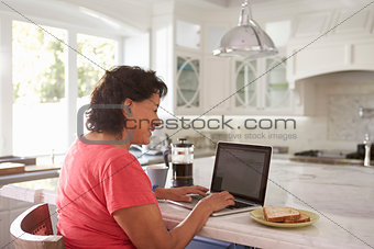 Senior Hispanic Woman Sitting At Home Using Laptop