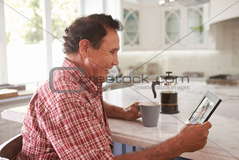 Senior Hispanic Man At Home Looking At Old Photograph