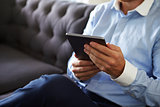Close Up Of Man Sitting On Sofa Using Digital Tablet