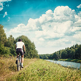 Cyclist Riding a Bike on River Bank. Toned Photo.