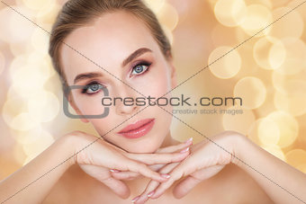 beautiful young woman face and hands over lights