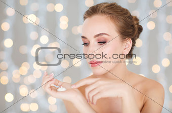 woman with moisturizing cream on hand over lights