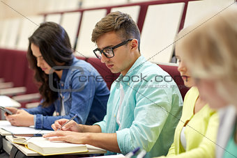 group of students with books writing at lecture